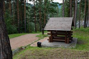 Wooden bench shelter in the forest with a dirt path. photo