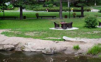 Outdoor wicker furniture set by a stream in a lush garden. photo
