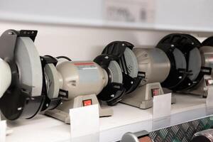 Various grinding machines displayed on a shelf in a tool store during daylight hours photo