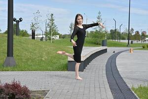 A woman calmly waiting in front of a parking lot entrance, with city buildings and cars in the background. photo