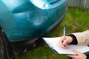 damaged car bumper with a person filling out a form on a tablet, getting insurance. photo
