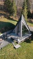 A-frame house with outdoor seating area - An A-frame house with a spacious deck, hot tub, fire pit, and outdoor seating area surrounded by greenery and trees on video