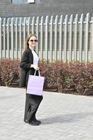 She is dressed in a crisp white top paired with a black blazer, creating a stylish and elegant look suitable for a day out shopping or strolling in the city. photo
