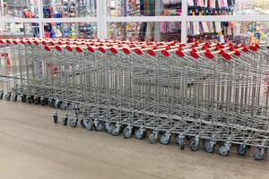 Metallic shopping carts arranged in neat rows within a retail store, showcasing the organization and preparation for shoppers during peak hours. photo