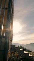 Wooden structure with sunlight and mountain view at sunrise - A modern wooden structure with sunlight streaming through slats, set against a backdrop of rolling video