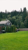 Modern Cabins with Large Lawn and Forest View. Two modern cabins with sleek designs and green metal roofs, set on a large manicured lawn with a fenced boundary video