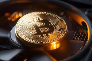 Golden Bitcoin coin resting on dark high-tech computer cooling fan symbolizing digital finance technology photo