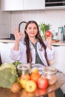 nutritionist in a white coat holding an apple in her hands among fresh products. health concept, fitness. photo