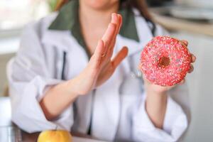 Nutritionist shows a sugary donut as an example of an unhealthy choice and its impact on health. Health and nutrition concept. photo
