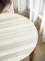Modern round tabletop bathed in striped sunlight from a nearby window photo