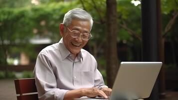 An older man sitting on a bench with a laptop photo