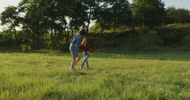 Two women are jumping and having fun standing in a meadow on a summer day. Summer holidays, carefree time photo