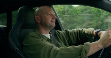 A man smiles and dances while driving a car. View from the car interior. Summer day photo