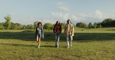 Three friends are smiling and talking while walking in the park on a sunny summer day. photo