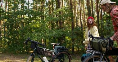 A man and a woman get on their bicycles and start riding through the forest on a sunny day photo