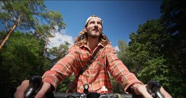 A man drinks water while riding a bicycle on a sunny day. Front view photo