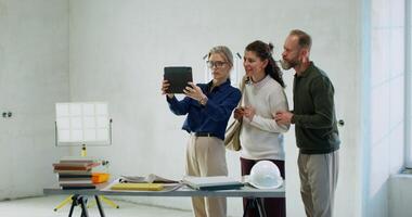 The designer uses a tablet to visualize the interior. She talks to customers while standing at a construction site photo