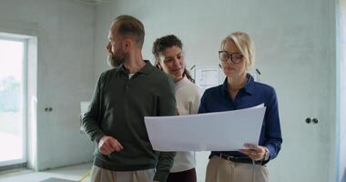 A married couple and a designer discuss the design of a house while standing indoors without decoration photo