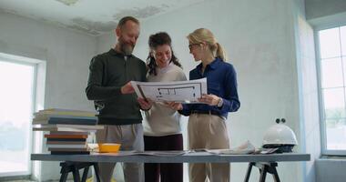 Happy customers study the design project of the house with the designer. Work on a construction site photo