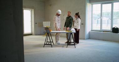 The foreman is talking to a married couple, discussing a house construction project photo