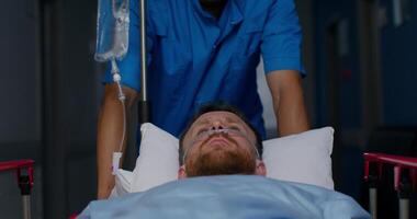 An orderly carries a patient with an oxygen tube in his nose on a trolley along the hospital corridor photo