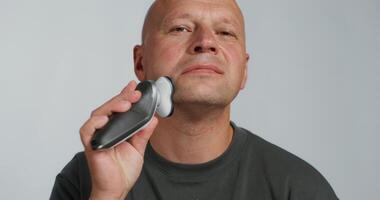 A bald man is holding a small electronic device photo