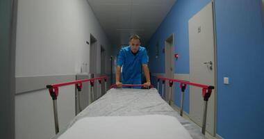 An orderly carries an empty gurney along the hospital corridor. Work at the clinic photo