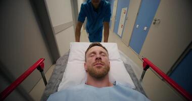 A man is lying on a medical gurney, he is being driven through a hospital corridor, his eyes are closed photo