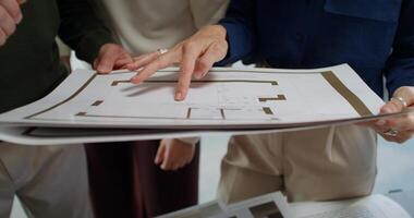 The designer shows the project of the house to the clients. Close-up of their hands, unrecognizable persons photo