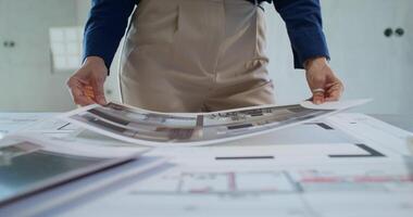 A businesswoman studies the design project of a house while standing in a room without decoration. Close-up of her hands, an unrecognizable person photo