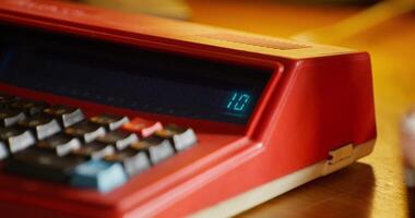 A woman's hand enters numbers on an outdated calculator. Retro office desktop close-up. An unrecognizable person photo