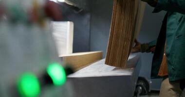 Working in a paper mill. A man drops stacks of cardboard into a machine photo