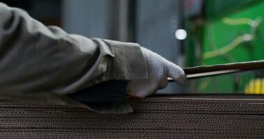 Cardboard production. Close-up of the hands of factory workers in protective gloves. The cardboard sheets are stacked photo