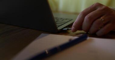 A woman inserts a charging cable into a laptop, close-up of her hands, an unrecognizable person photo