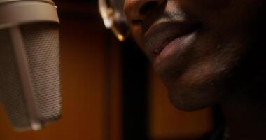 A rapper sings into a microphone in a recording studio. Close-up of his mouth, an unrecognizable person, photo