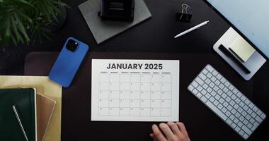 A man highlights date in a calendar while sitting at a table. Planning while working in the office. Close-up of his hands photo