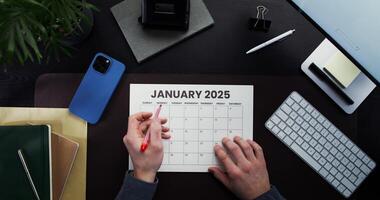 The man crosses out the month and year in the calendar with a red marker. Close-up of his hands, working in the office photo