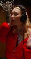 A woman sings into a professional microphone in the studio. The singer during work photo