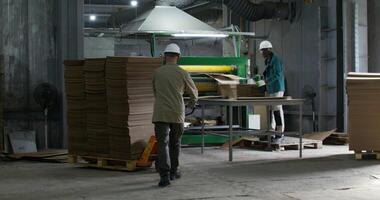 Working in a paper mill. One of the men controls the operation of the machine, the second man brings a pallet with cardboard on a cart photo