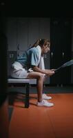 Young beautiful woman tennis player is resting in the locker room after the match, sitting on a bench with a towel around her neck and twirling a tennis racket in her hands, vertical photo