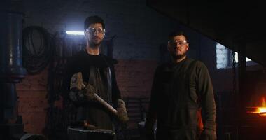 Two men in blacksmithing gear standing in front of a furnace photo