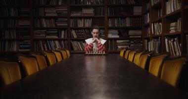 A man sitting at a table in front of bookshelves photo