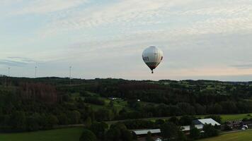 A drone shot, a view of a hot air balloon in the sky, flying over neat village houses, located among the green expanse. photo