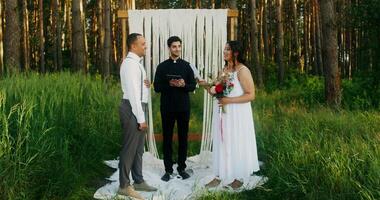 The bride smiles looking at the groom when reading the oath during the wedding outdoors photo