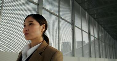A woman in a coat looks at the camera with a concentrated look standing at the train station, close-up of her face photo