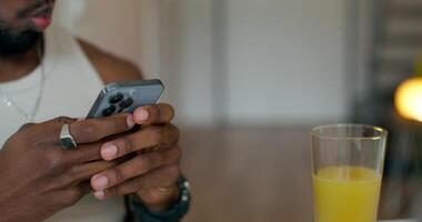 A man uses a mobile phone sitting at a table indoors. Close-up of his hands, an unrecognizable person photo