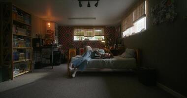 A woman uses a mobile phone lying on the bed. She is typing and taking selfies with a sad look photo