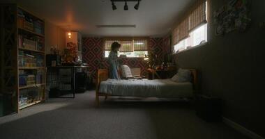 A young woman in casual clothes uses a mobile phone at home with a serious look. She sits down on the bed photo