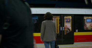 A stylish woman stands on a subway platform. The train is going past her. Rear view, unrecognizable person photo