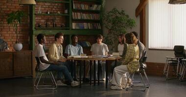 Young people of different nationalities get up from the table, hold hands and begin to pray. Daylight photo